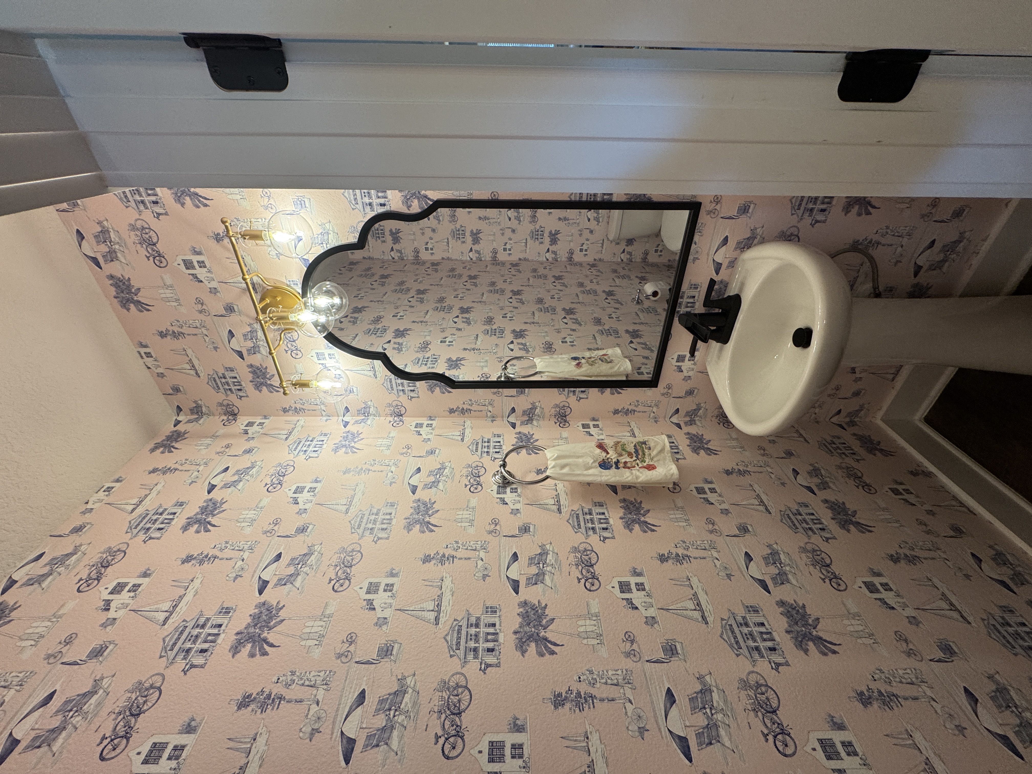 Pink coastal toile wallpaper surrounding a finished powder room