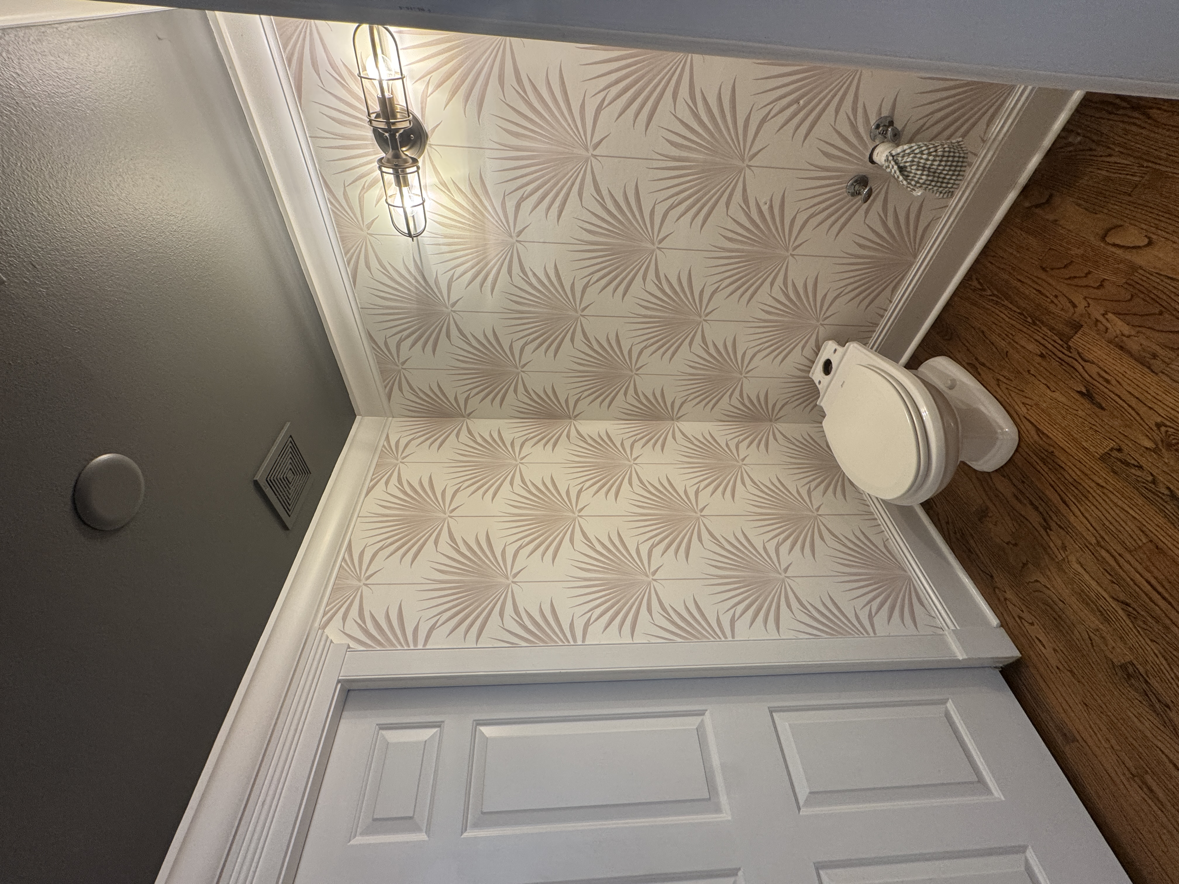 Pale palm wallpaper wrapping around a powder room corner